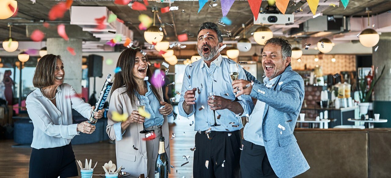 Four colleagues celebrating with confetti and champagne