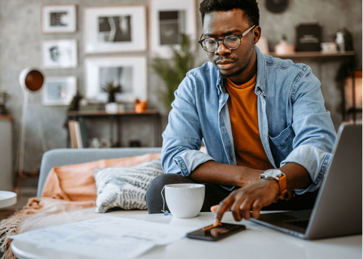 African-American man using smartphone and laptop and drinking tea