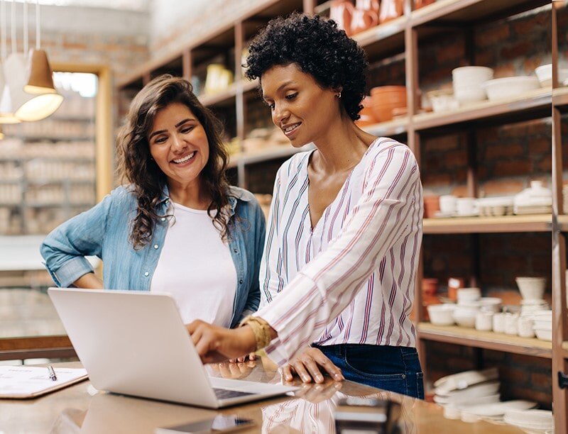 Two female entrepreneurs managing online orders in their pottery store.