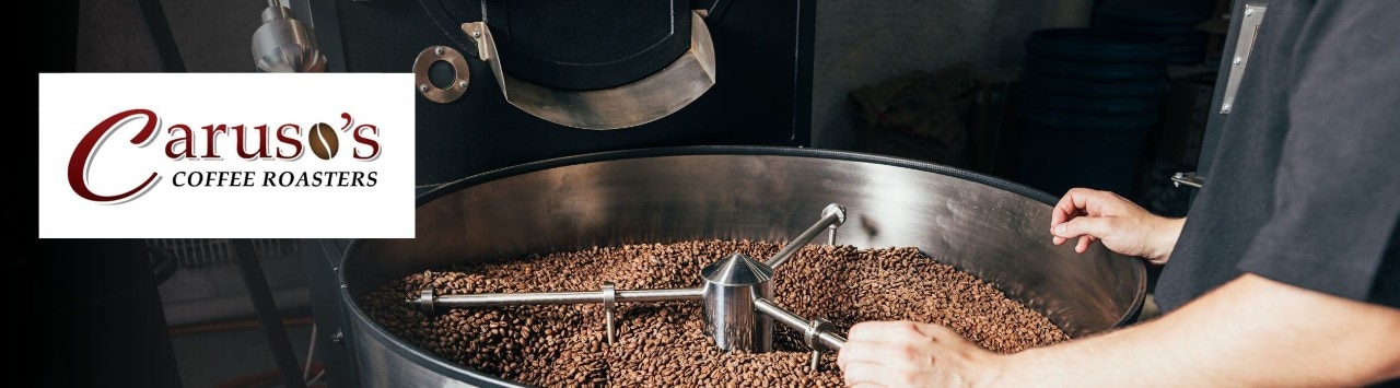 A person observes coffee beans roasting in high-capacity drum. 