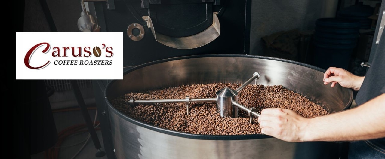 A person observes coffee beans roasting in high-capacity drum. 