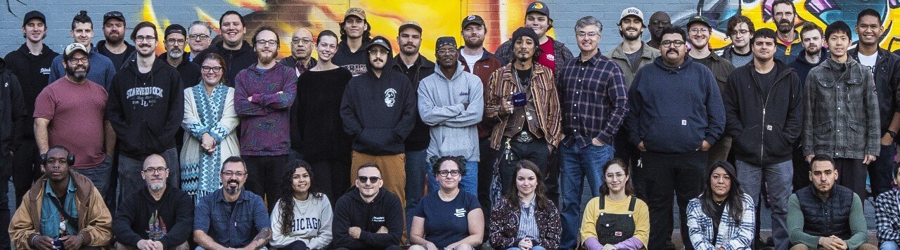 A group photo of the Bridgewater company in front of a mural