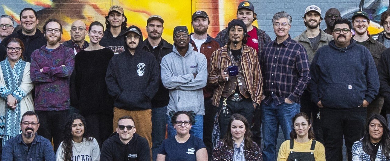 A group photo of the Bridgewater company in front of a mural