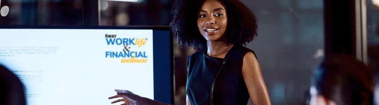 Female banker presenting in front of video screen with First WORKlife® and Financial Wellness logo