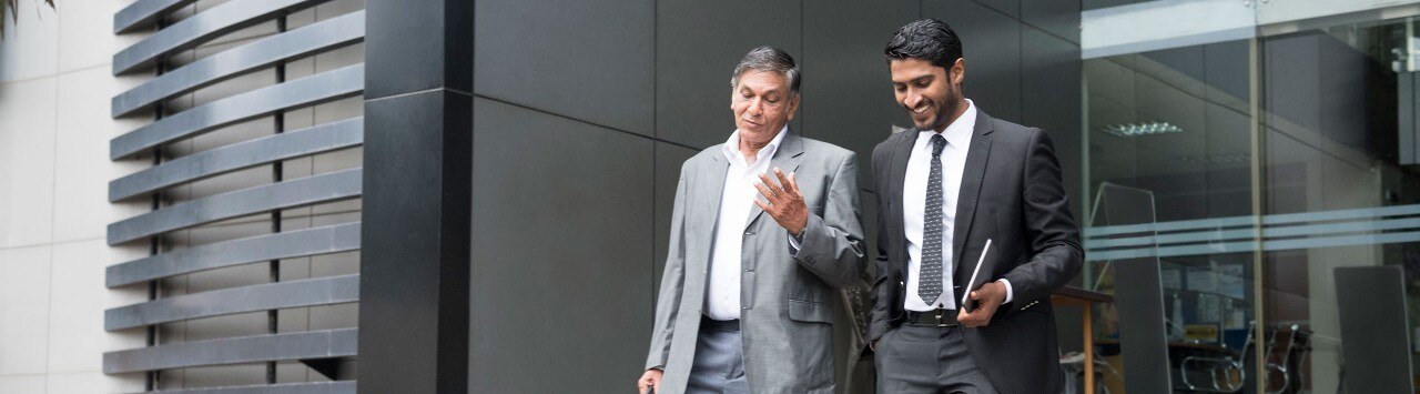 Older businessman talking with younger colleague as they leave the office