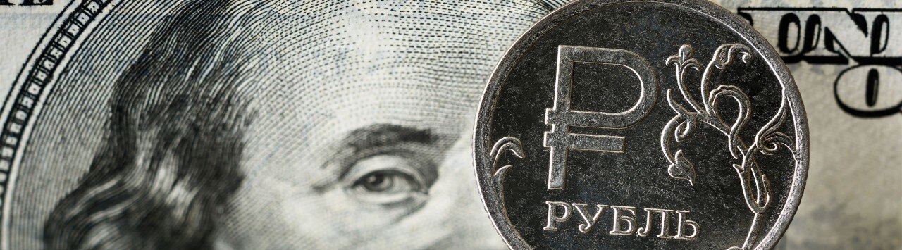 Russian Ruble coins with an American $100 bill in the background