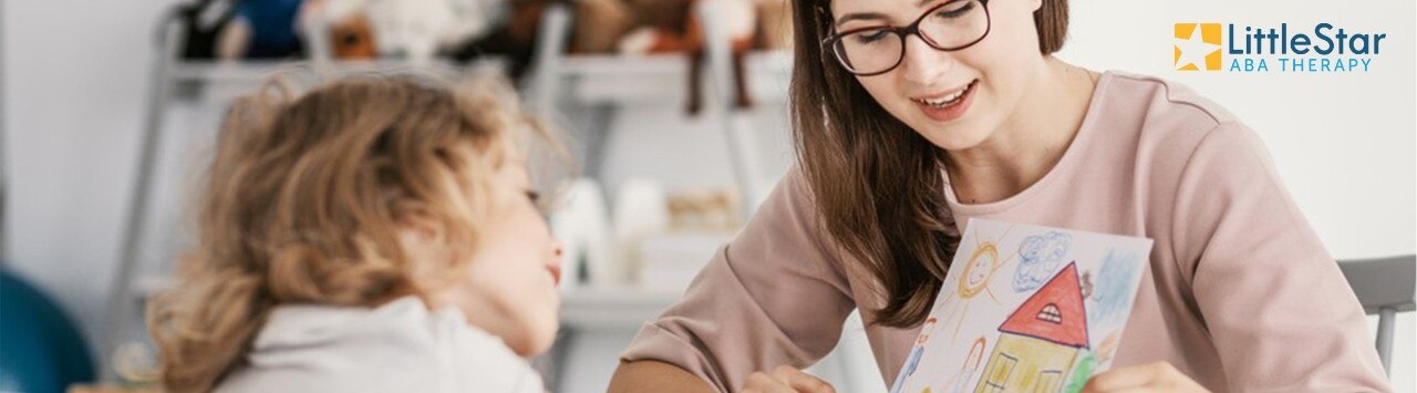 Woman and young girl looking at girl's drawing, with LittleStar ABA Therapy logo in corner