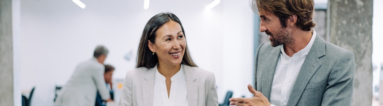 Female and male colleagues conversing outside conference room