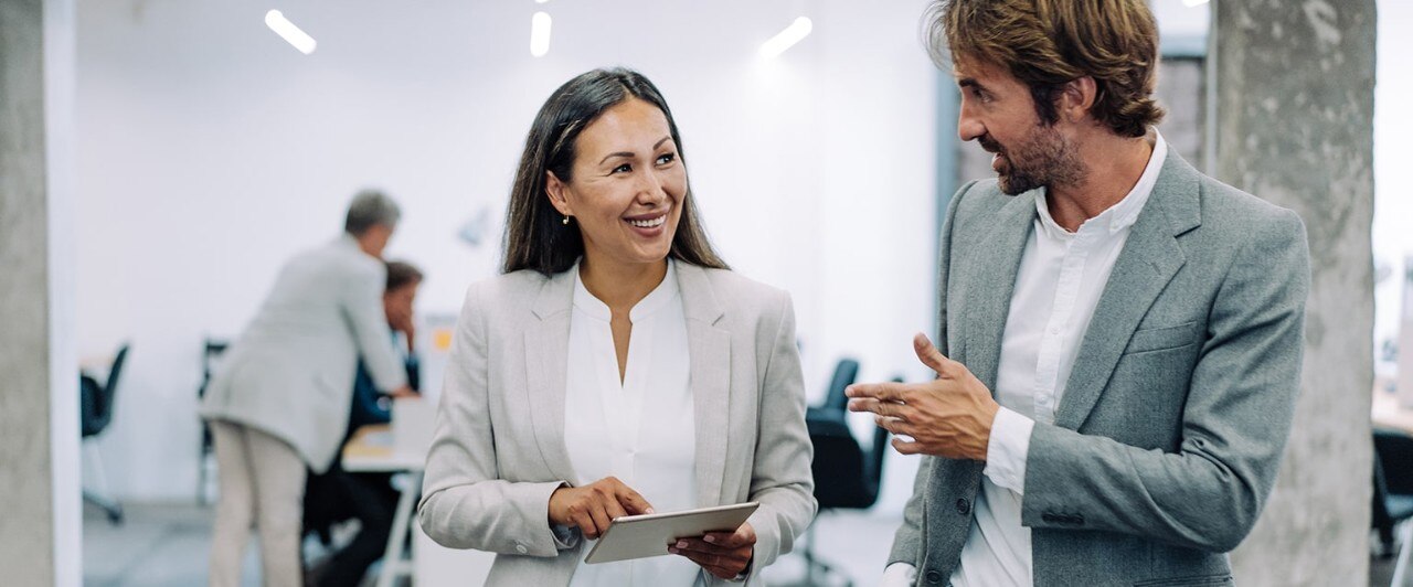 Female and male colleagues conversing outside conference room