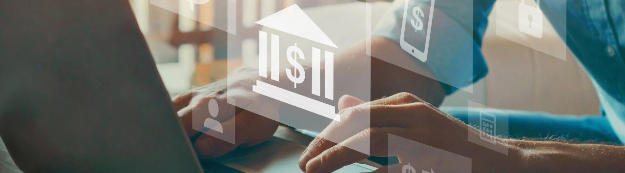 Hands working at laptop with superimposed financial icons floating in the air