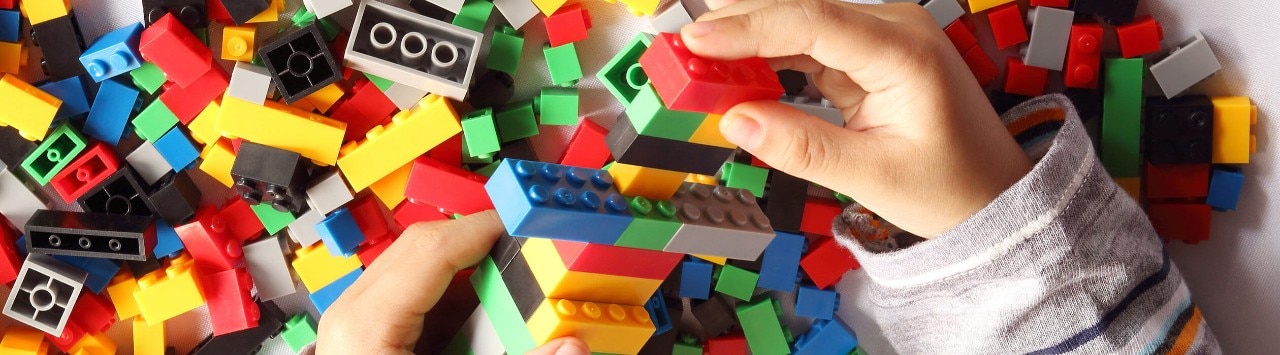 Close up of child's hand playing plastic toy building blocks