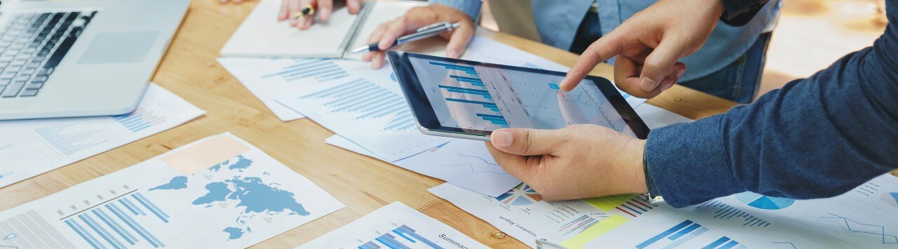 A group of people around a table with charts and graphs and a tablet
