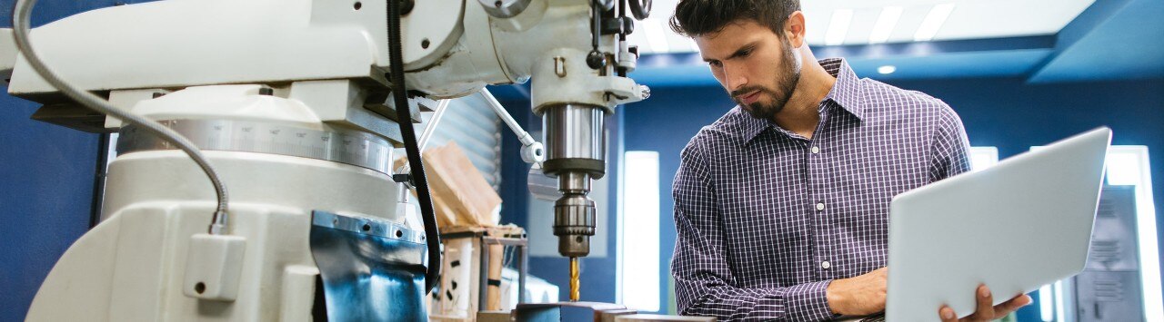 A man with a laptop looks over machinery