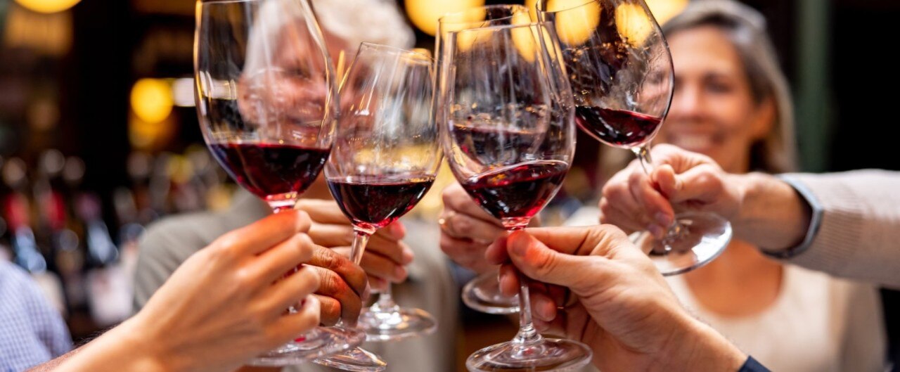 Group of friends toasting with glasses of red wine