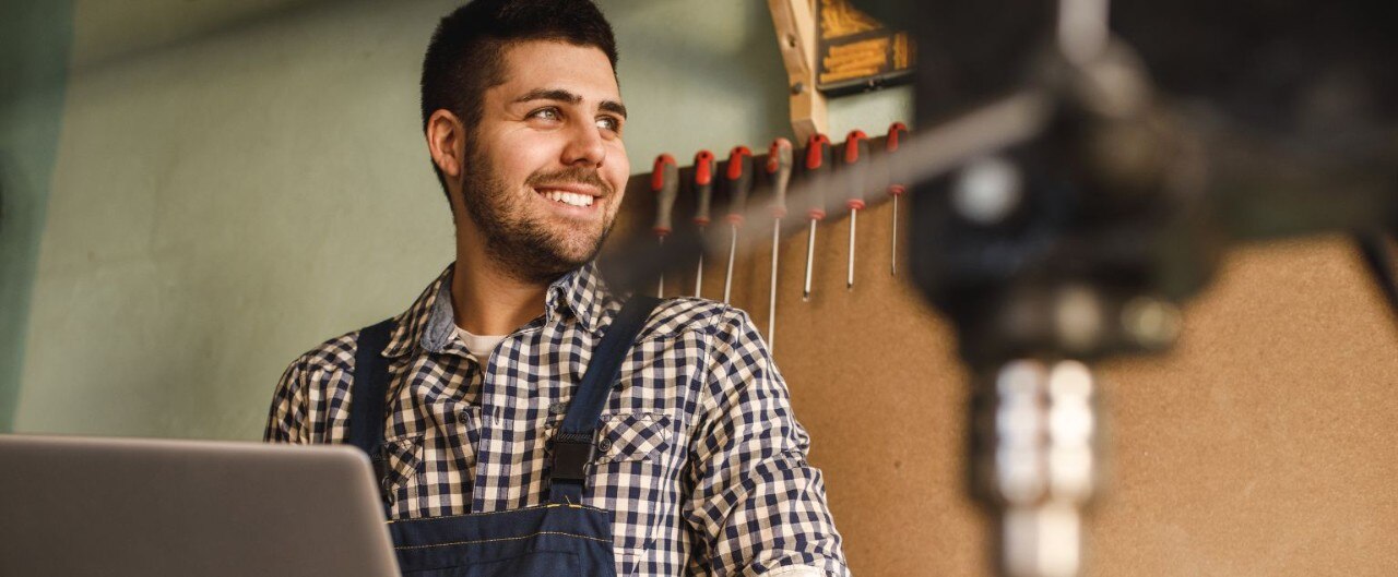 Smiling small business owner surrounded by tools in workshop
