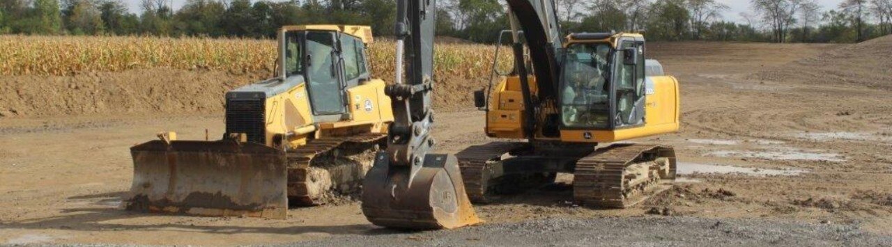 Heavy equipment including a bulldozer and excavator sitting in a field