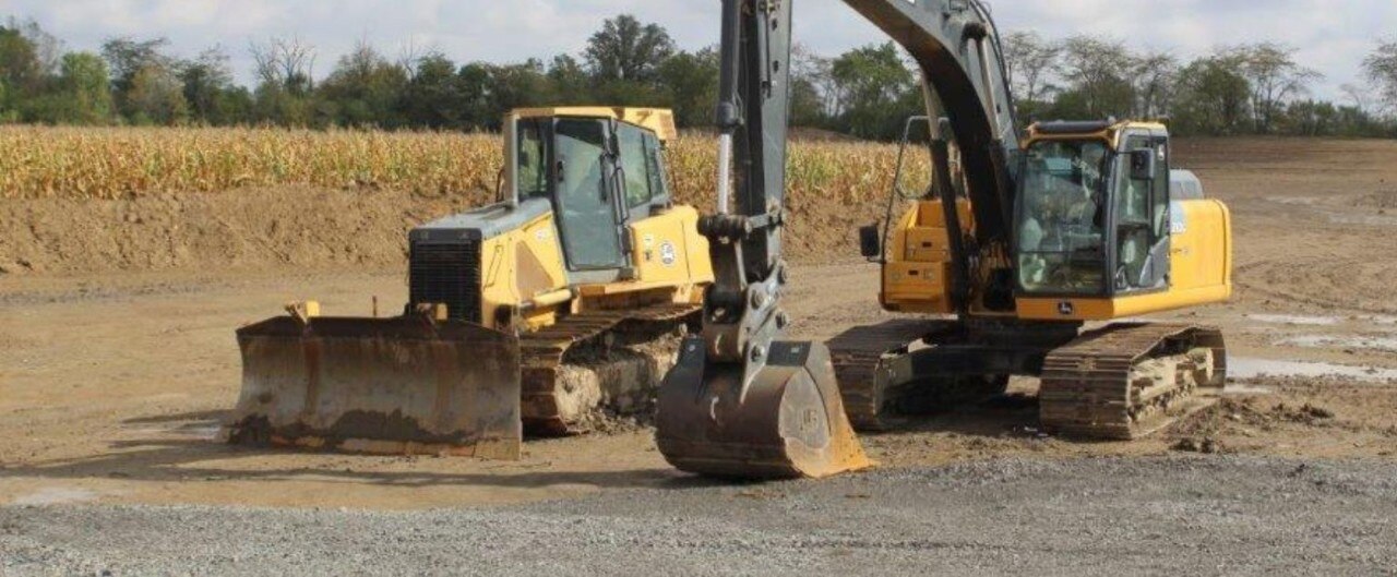 Heavy equipment including a bulldozer and excavator sitting in a field