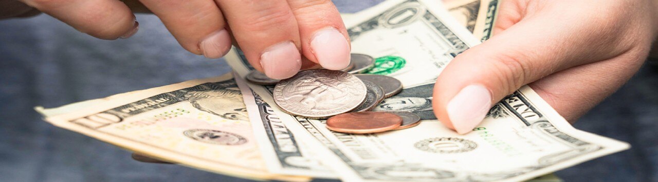 Woman's hands holding American currency in various forms