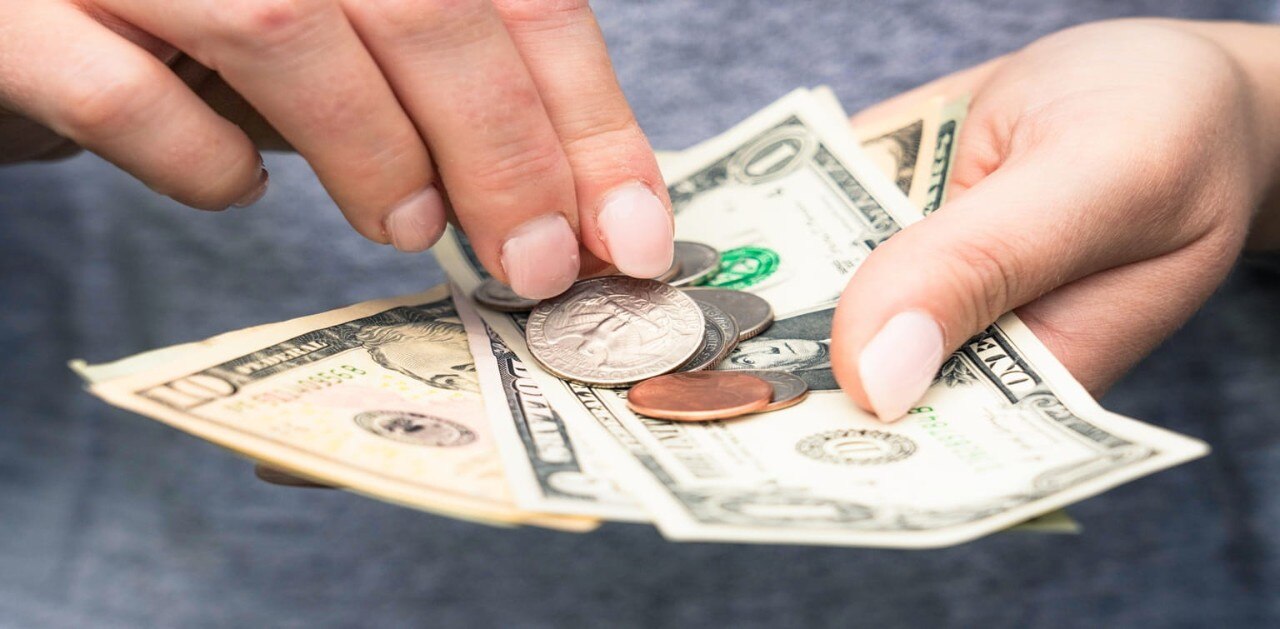 Woman's hands holding American currency in various forms