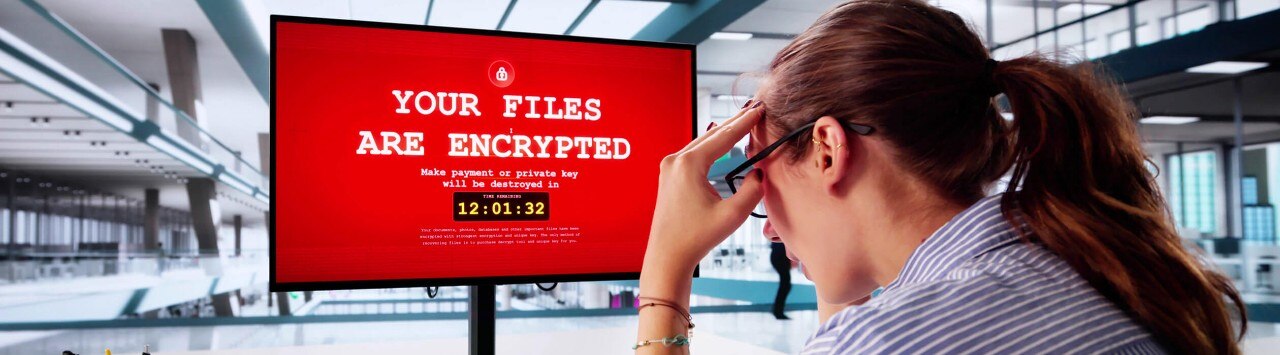 Stressed out businesswoman looking at her computer which has been infected with ransomware