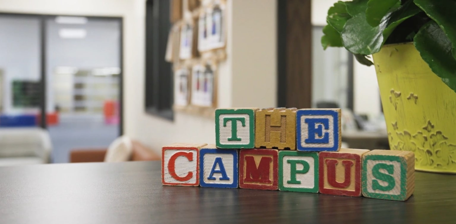 Children’s blocks arranged on a counter to spell “The Campus.” 