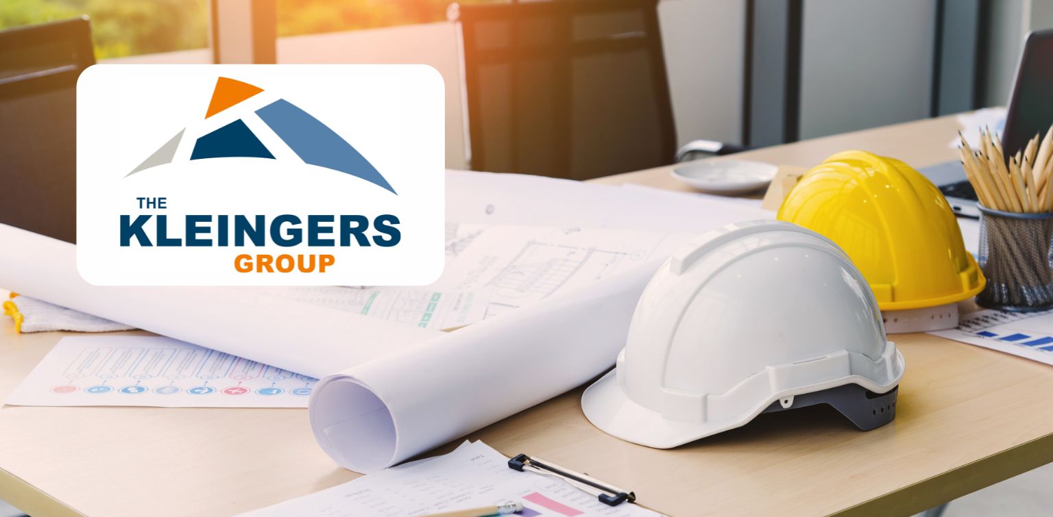 A desk with hard hats, blueprints, and pencils. Overlay of a logo, “The Kleingers Group.”