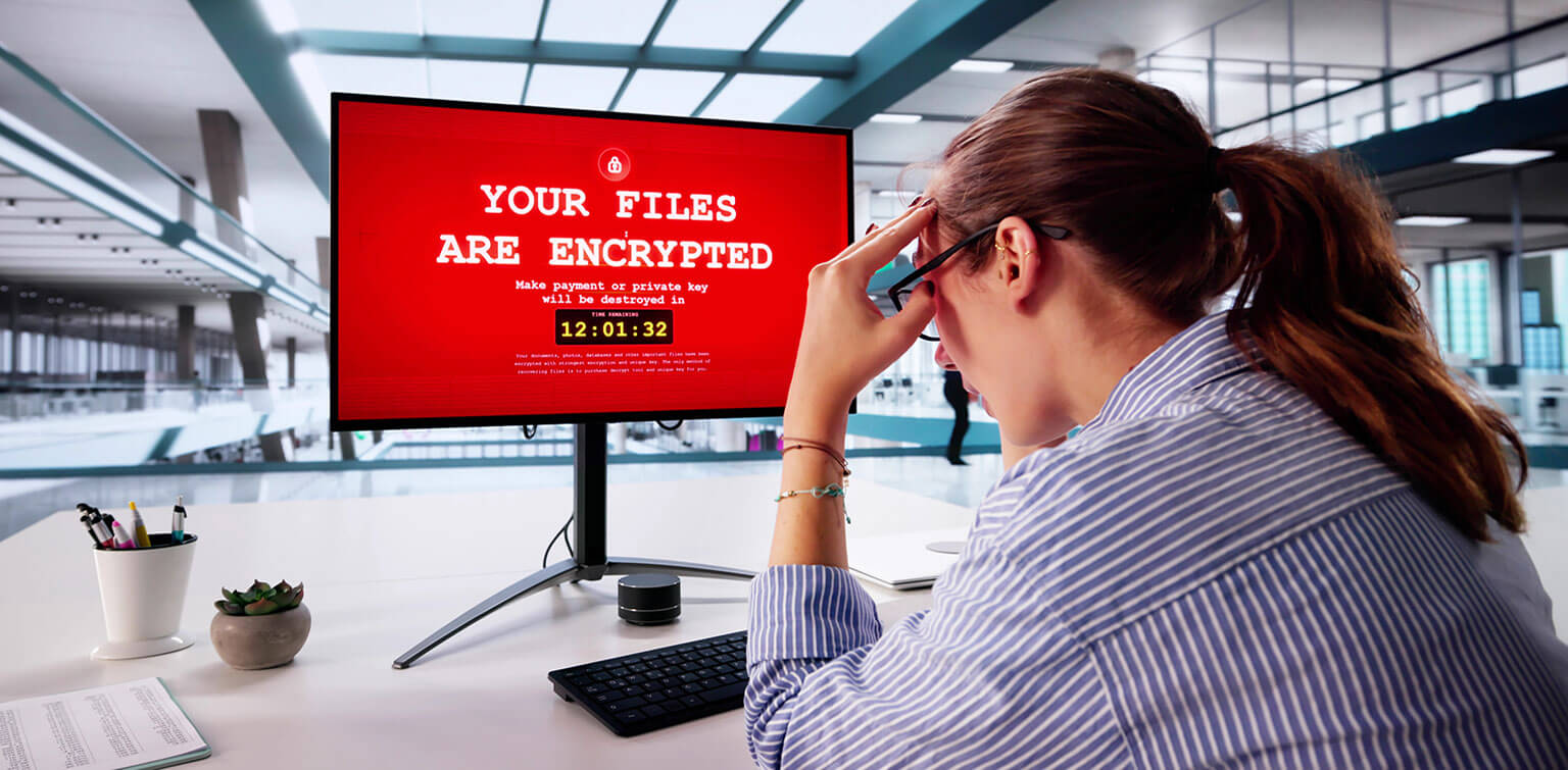 Stressed out businesswoman looking at her computer which has been infected with ransomware