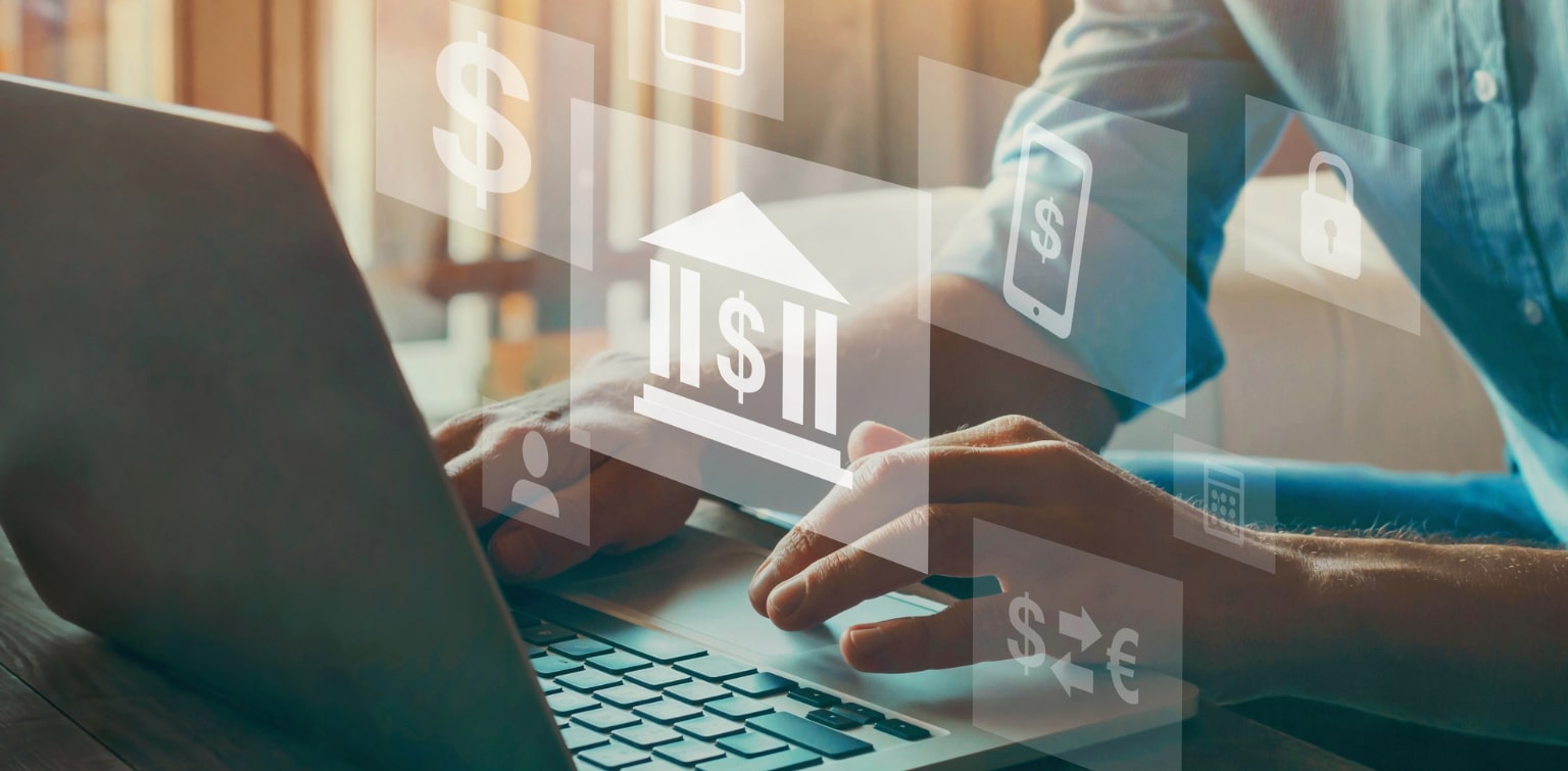 Hands working at laptop with superimposed financial icons floating in the air