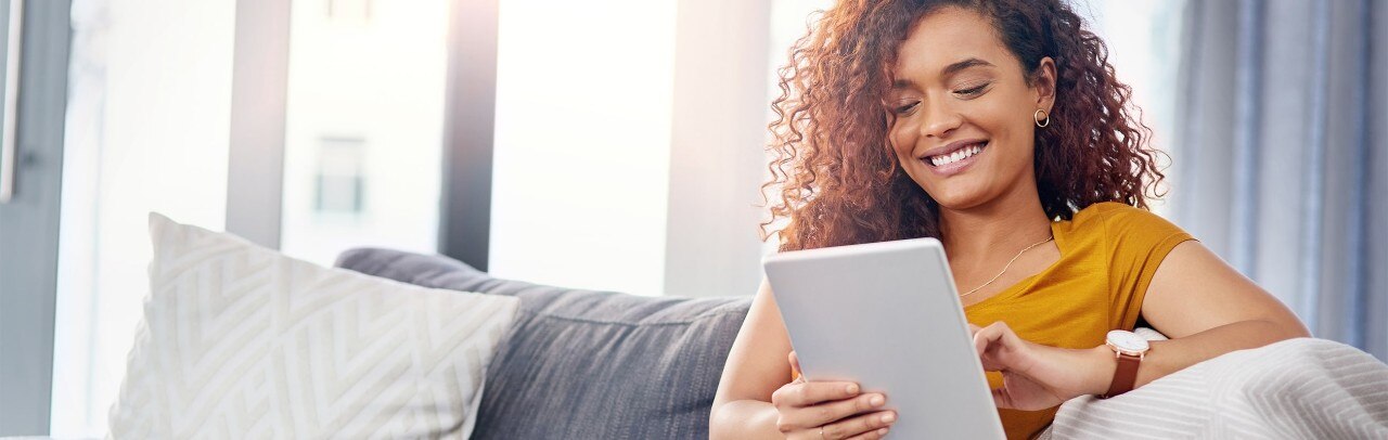 Lady relaxing on couch, looking at tablet