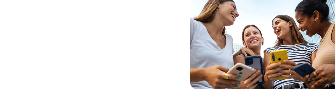 Four smiling young women using smartphones