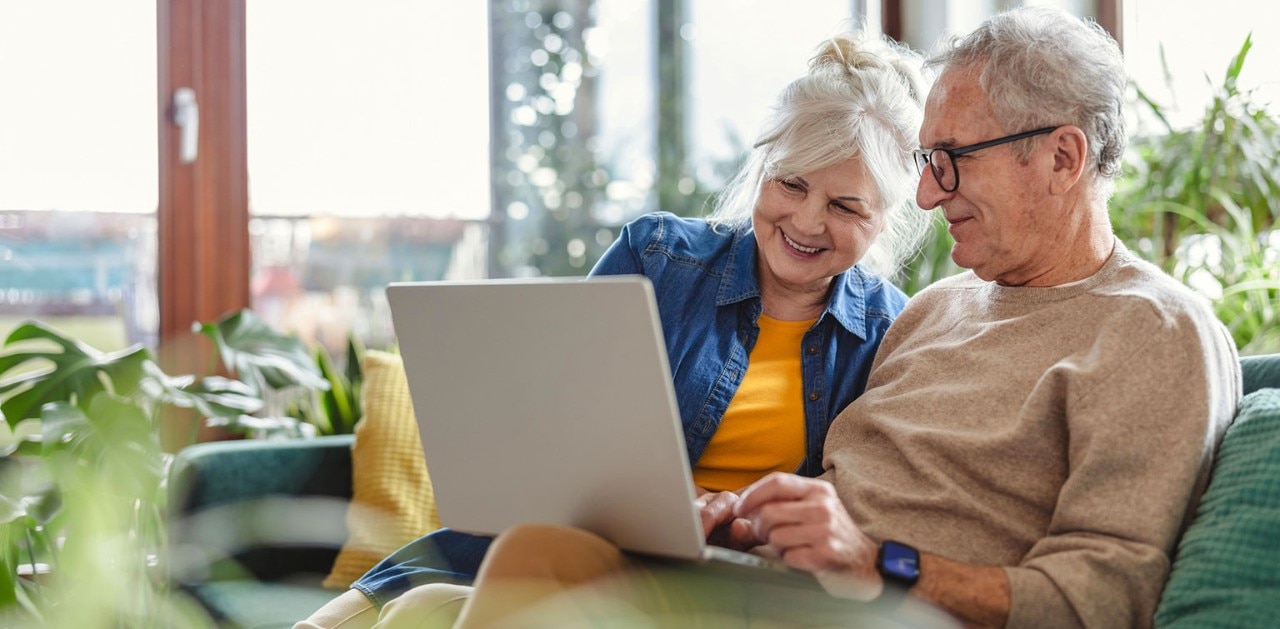 Senior couple using laptop, surrounded by houseplants