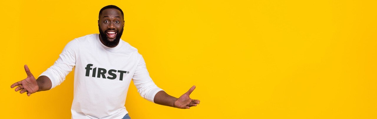 Happy man with outstretched arms wearing a First Financial Bank t-shirt against a yellow background