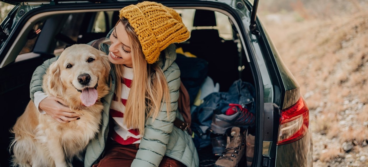 Woman hugging golden retriever sitting in the back of SUV