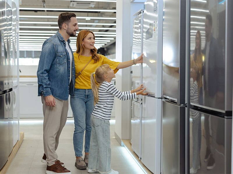 Couple and young daughter refrigerator shopping in an appliance store