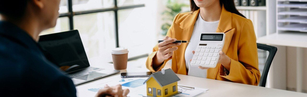 Mortgage loan office showing figures on a calculator to a client