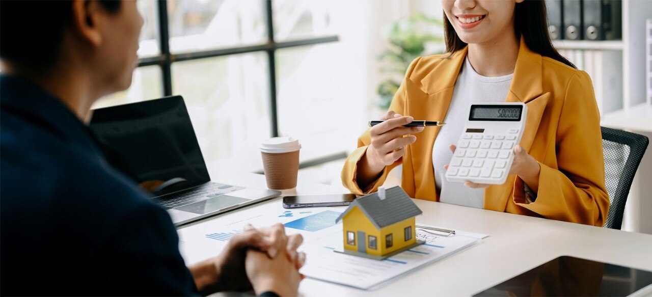 Mortgage loan office showing figures on a calculator to a client