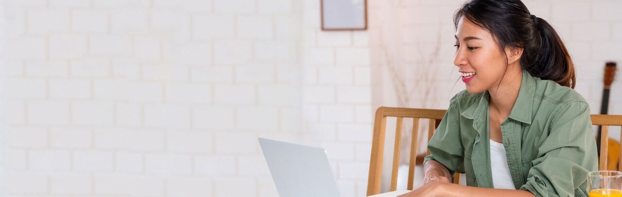 Young Hispanic woman at dining table working on laptop
