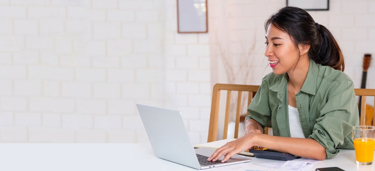 Young Hispanic woman at dining table working on laptop