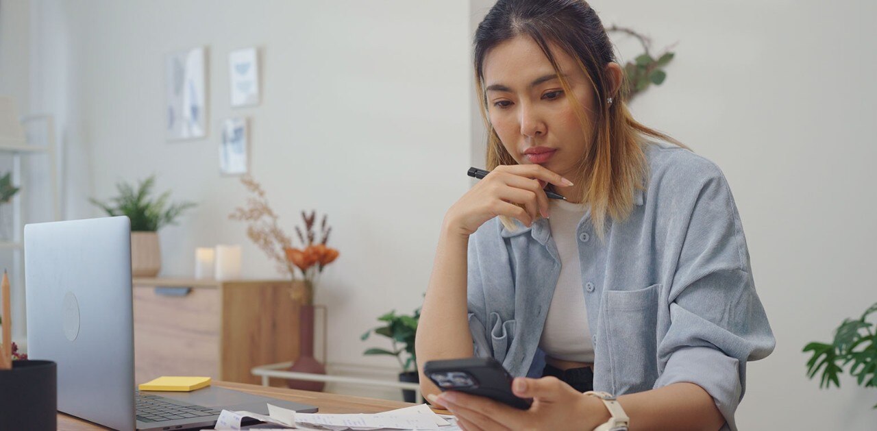 Asian-American woman looking thoughtfully at smartphone