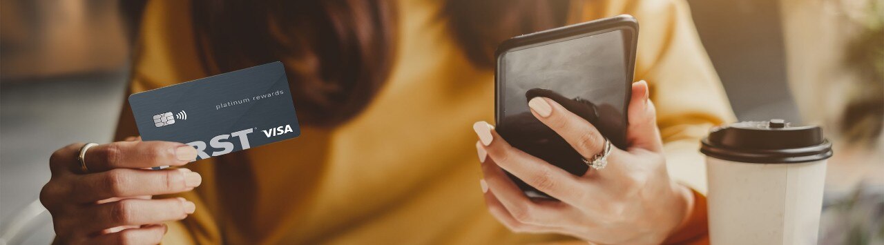 Asian woman holding First Financial credit card and looking at smartphone