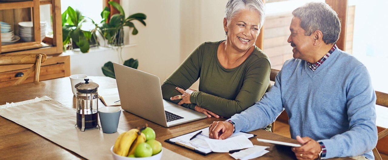 Smiling senior couple reviewing finances at a laptop