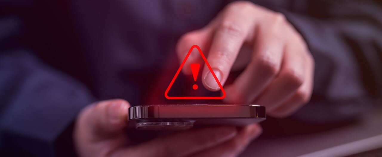 man on his phone with a red exclamation mark above it