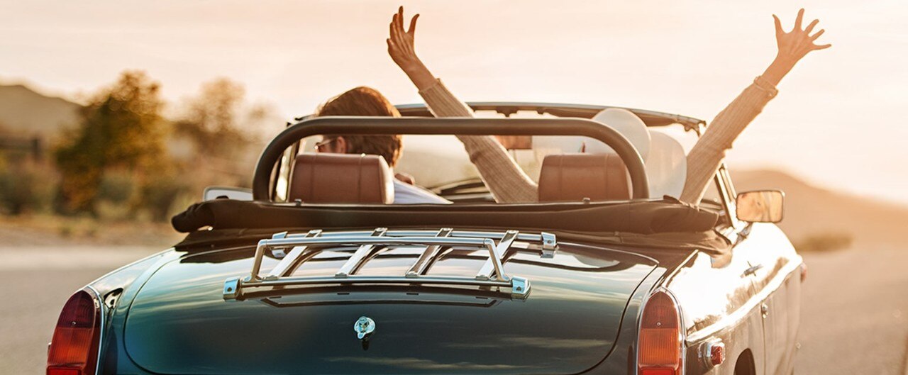 Young couple driving classic convertible on highway