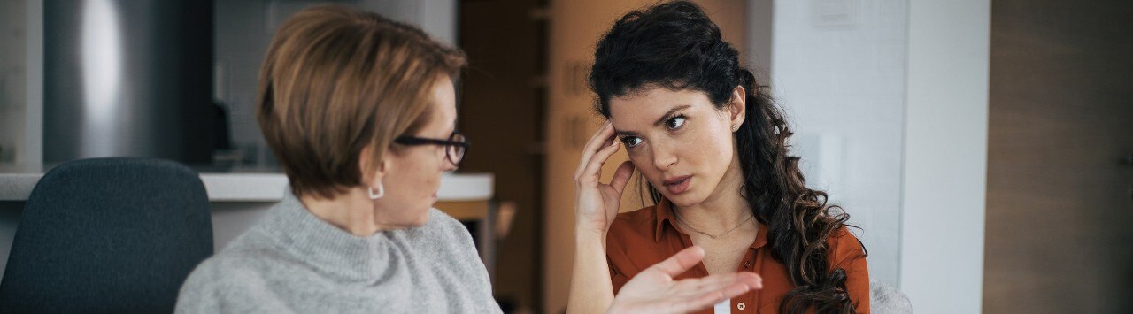 Mother and daughter engaged in convrsation on a couch as they exchange ideas about financial planning