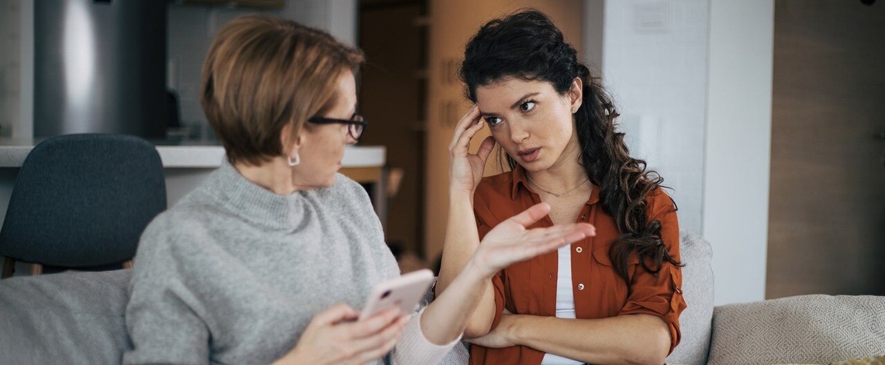 Mother and daughter engaged in convrsation on a couch as they exchange ideas about financial planning