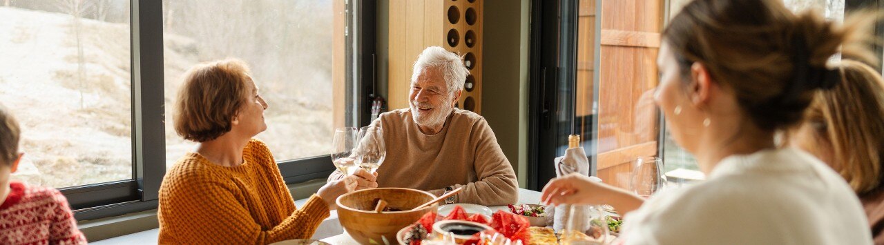 Senior couple and family members gathered around dinner table