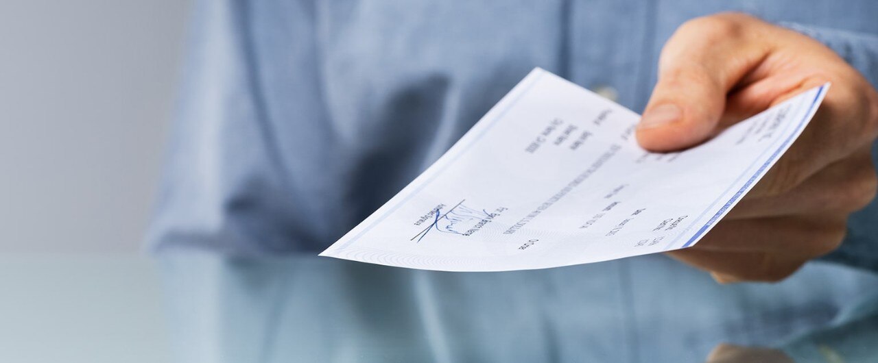 Man holding a check as he hands it to another person