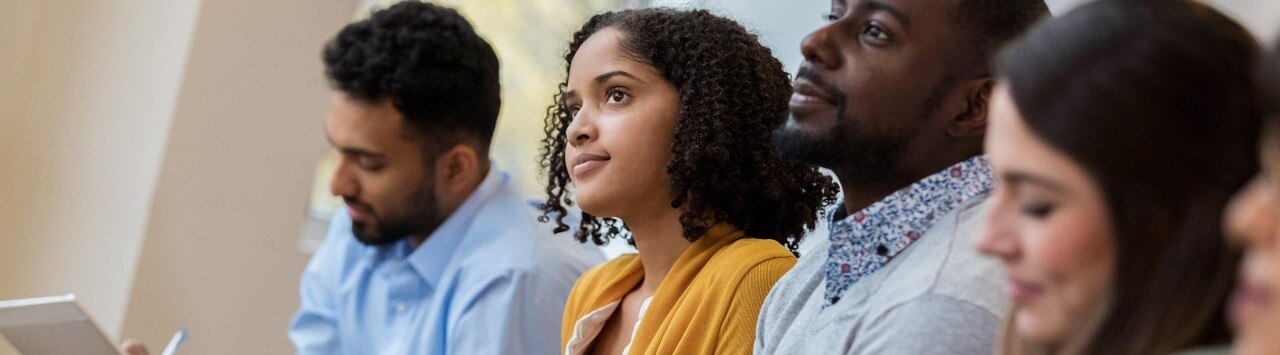 Diverse event attendees listening to a presentation and taking notes
