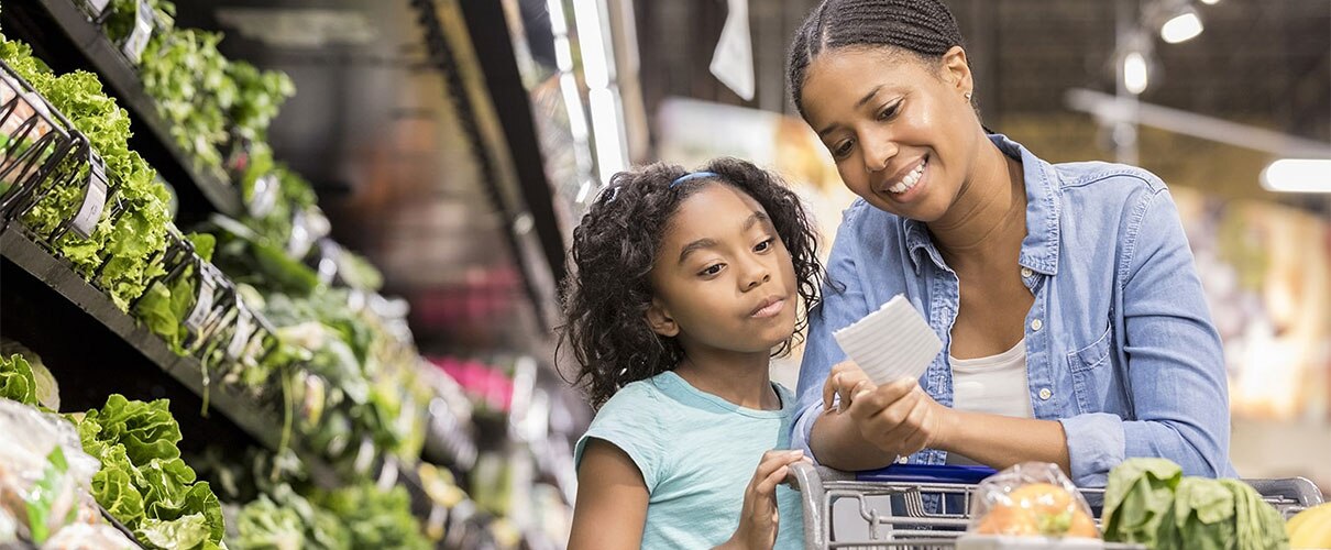 African-American mother and daughter grocery shopping in produce aisle