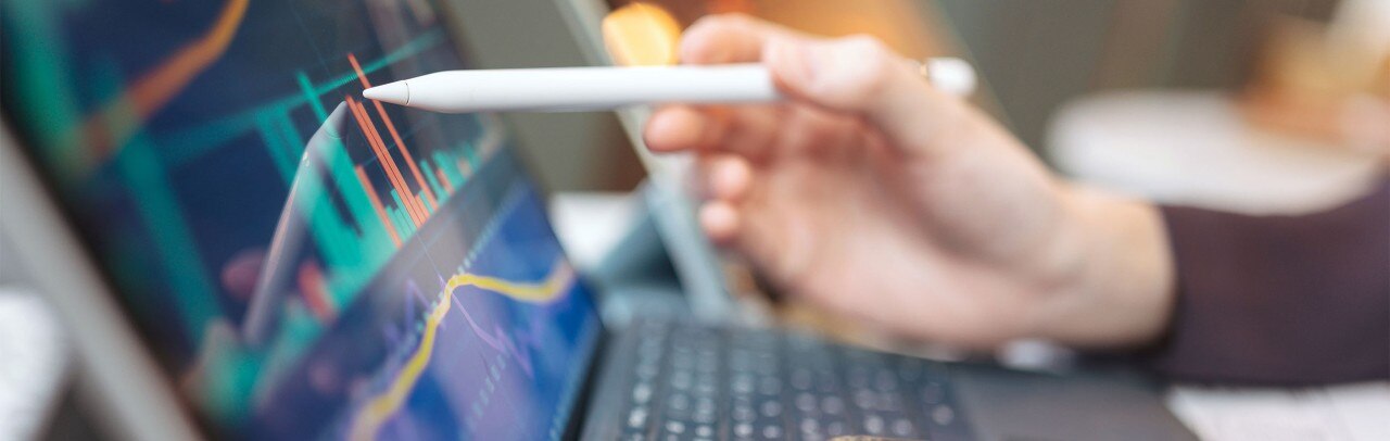 Person pointing a stylus at a digital display of financial data